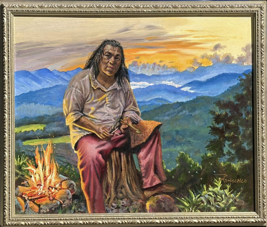This Land is Your Land 20×24″ oil on panel, framed by the artist Everywhere I go, I am looking for inspiration. A few weeks back, we were able to stay in a home on a creek in the Great Smoky Mountains. The painting depicts a native American member of the Eastern Band of the Cherokee Nation, in western North Carolina. We had a chance to visit the Oconaluftee Indian Village, where the 18th-century Cherokee lifestyle is preserved via live tool and craft demonstrations and authentic buildings. This gentleman was creating arrows for hunting the traditional way. And on the way back from Dry Falls, I captured this beautiful vista of the Smoky mountains at dusk, combining them to create this image of the craftsman, a reminder of who this land really belongs to. The light from the fire appears as war paint on his curious face. There is no judgment but there is a knowledge in his face that his people were on this land centuries before European colonists took it and made it their own land with their superior weaponry and patriotic songs